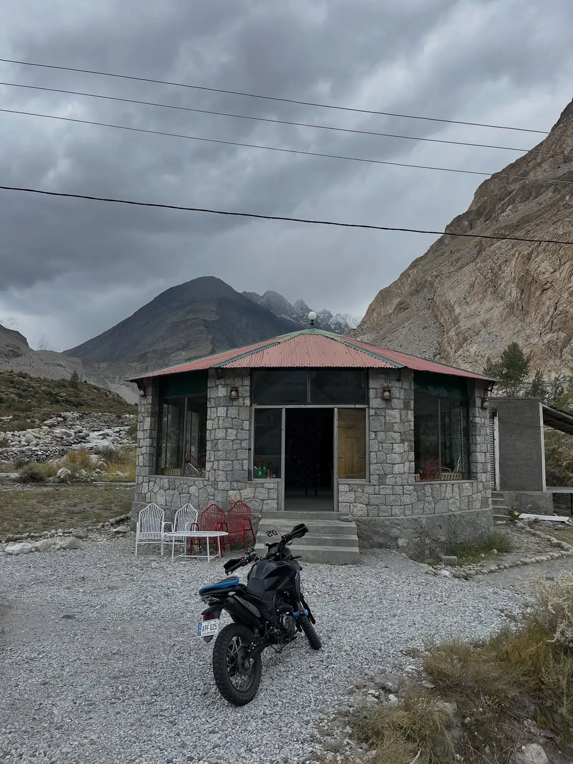 Motorcycle outside a mountain guesthouse beneath dramatic peaks